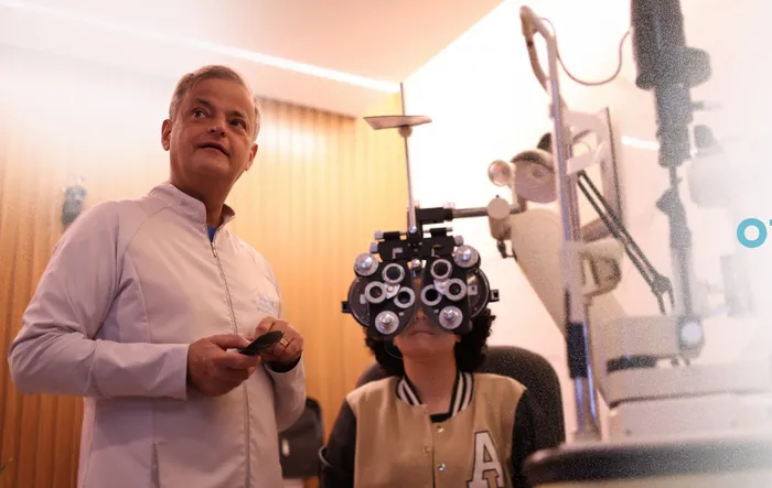 Oftalmologista do HOA realizando exame de vista com refrator em paciente